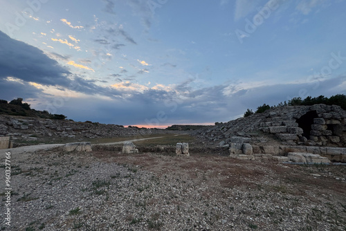 Ruins amphitheater sports arena gymnasium coliseum of ancient city in Türkiye, stone tribune architecture in beautiful nature under cloudy dramatic cinematic natural light sky