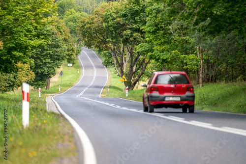 Fototapeta Naklejka Na Ścianę i Meble -  An asphalt road going through a forest in Masuria