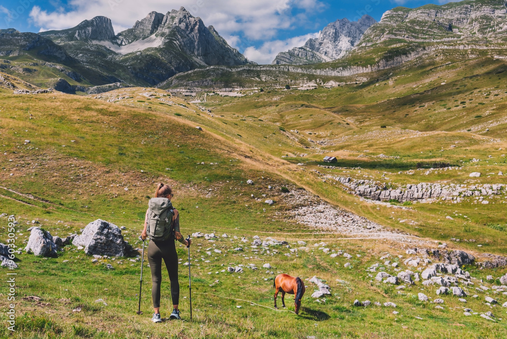 Woman Walking Down the Valley with Grazing Horse