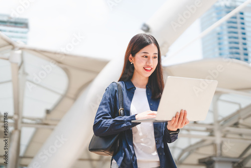 Canvas Print Business freelance adult asian woman using laptop standing on day building backg