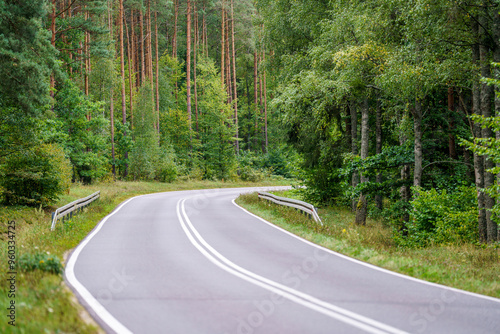 Fototapeta Naklejka Na Ścianę i Meble -  An asphalt road going through a forest in Masuria