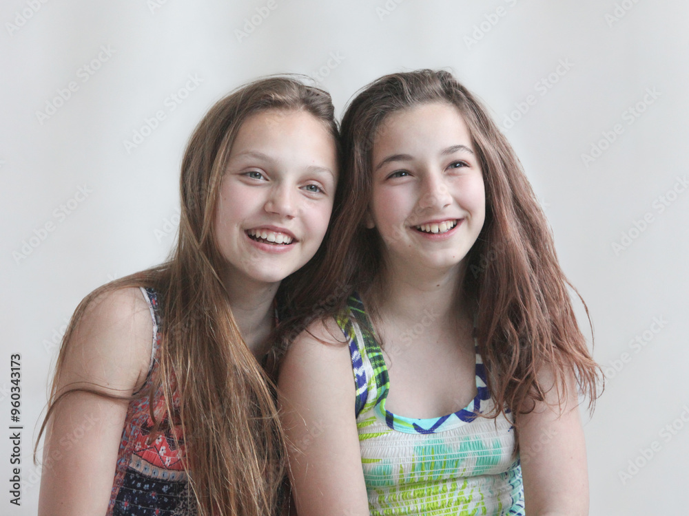 portrait of two happy little girls laughing on light background portrait of two happy little girls laughing on light background