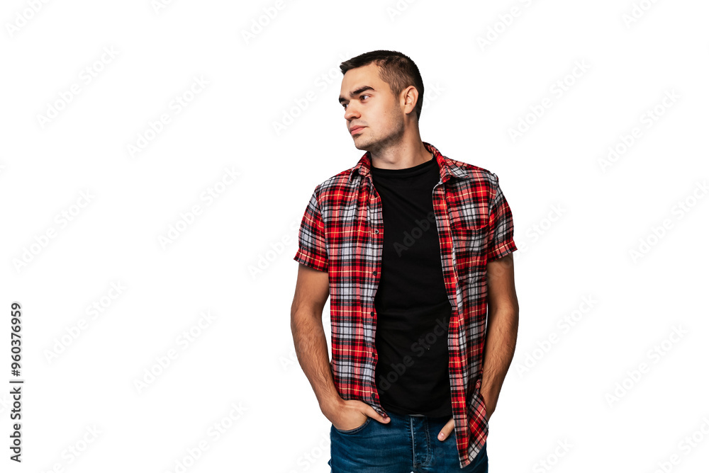 Young man in plaid shirt poses confidently against plain backdrop. A young man stands with his hands in his pockets, wearing a plaid shirt over a black t-shirt Young man in plaid shirt poses confidently against plain backdrop. A young man stands with his hands in his pockets, wearing a plaid shirt over a black t-shirt