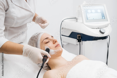 A cosmetologist performs RF lifting and ultrasound facial tightening in a modern salon. This advanced treatment rejuvenates and firms skin, perfect for showcasing effective beauty solutions. photo