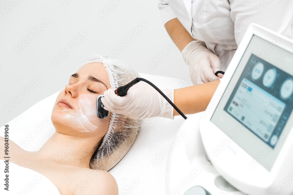 A cosmetologist applies radiofrequency lifting to a young woman in a modern clinic. This advanced procedure tightens skin and promotes rejuvenation, ideal for showcasing beauty treatments. A cosmetologist applies radiofrequency lifting to a young woman in a modern clinic. This advanced procedure tightens skin and promotes rejuvenation, ideal for showcasing beauty treatments.