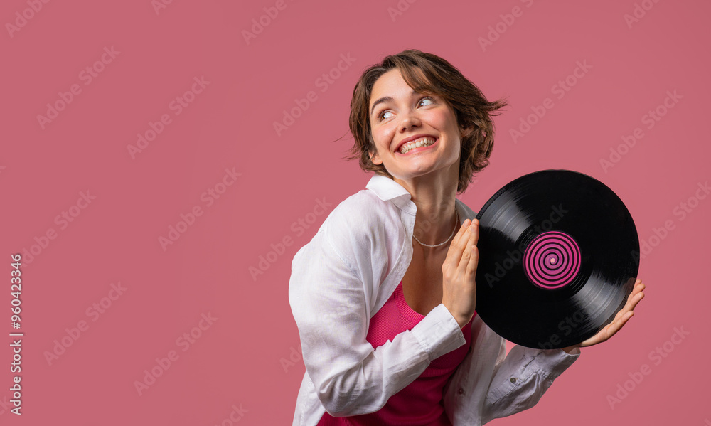 Positive short haired woman with vinyl record disc on pink. Hobby, music lover, collection, nostalgia lifestyle. Copy space. Positive short haired woman with vinyl record disc on pink. Hobby, music lover, collection, nostalgia lifestyle. Copy space.