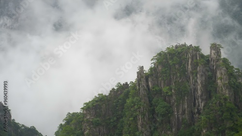 Mysterious high stone mountain with clouds in China Huangshan mountains surrounded by mist fog