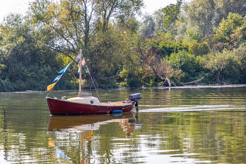 Wallpaper Mural Small boat anchored in calm waters of a reservoir tributary of Meuse river, autumnal leafy trees in background, sunny autumn day in South Limburg, Netherlands Torontodigital.ca
