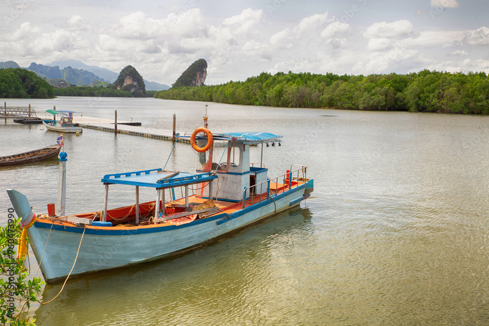thailand fishing boat moored on river pier against tropical forest background thailand fishing boat moored on river pier against tropical forest background