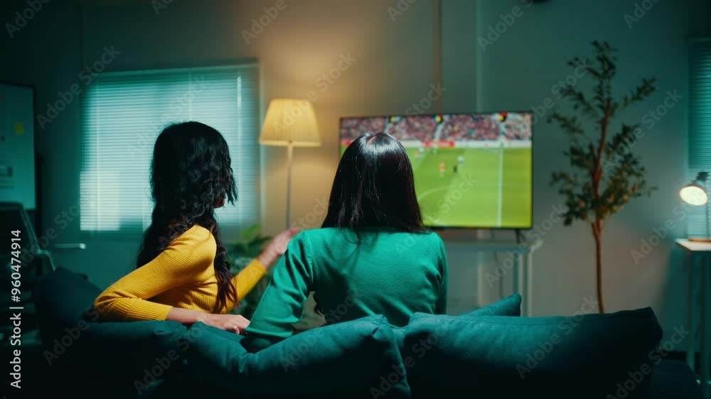 Two women sitting on a sofa are enjoying a football match on tv. They are discussing the game, sharing their excitement and passion for the sport Stock ビデオ | Adobe Stock