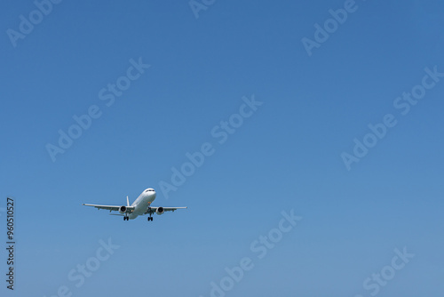 An approaching plane in the empty blue sky. A large expanse of empty sky.