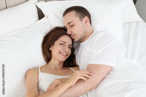 Cute couple lying in bed at home, top view