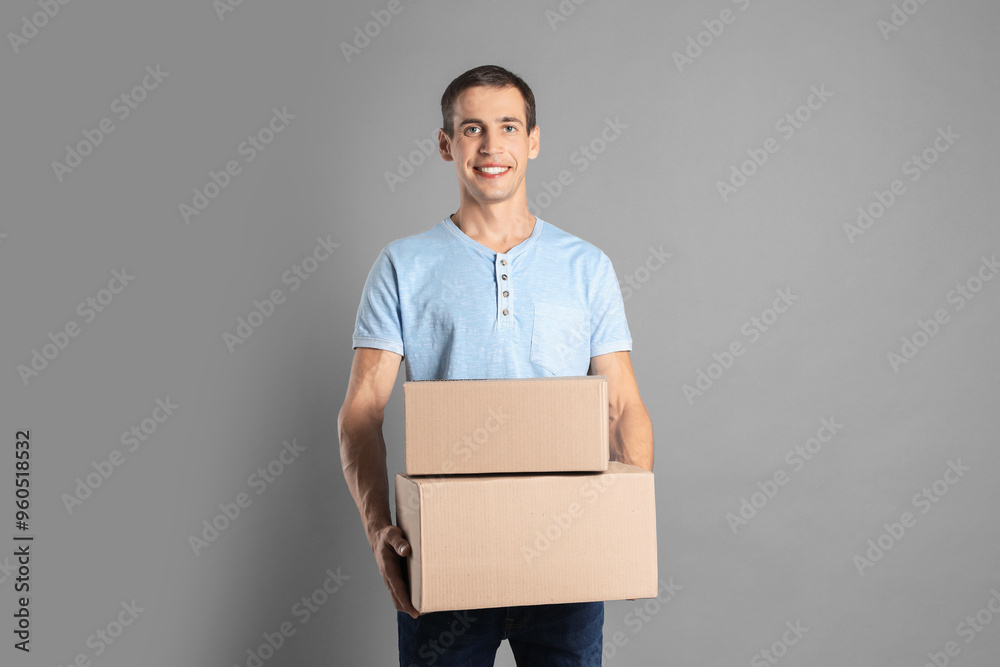 Moving into new house. Man with cardboard boxes on grey background, space for text Moving into new house. Man with cardboard boxes on grey background, space for text