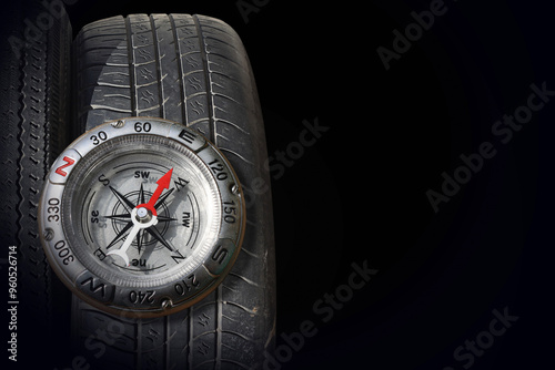 Classic compass and car tire on black background photo