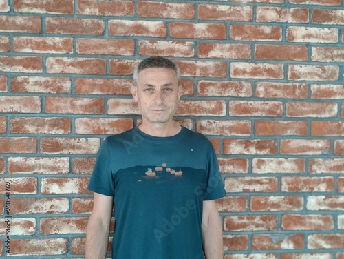 Portrait of a Middle-Aged Man in Front of a Brick Wall - Serious Expression, Calm Gaze, and Blue Eyes