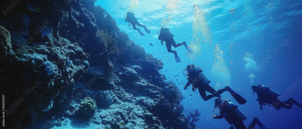 Fototapeta premium Divers Exploring Vibrant Reef Wall Beneath Crystal Blue Waters