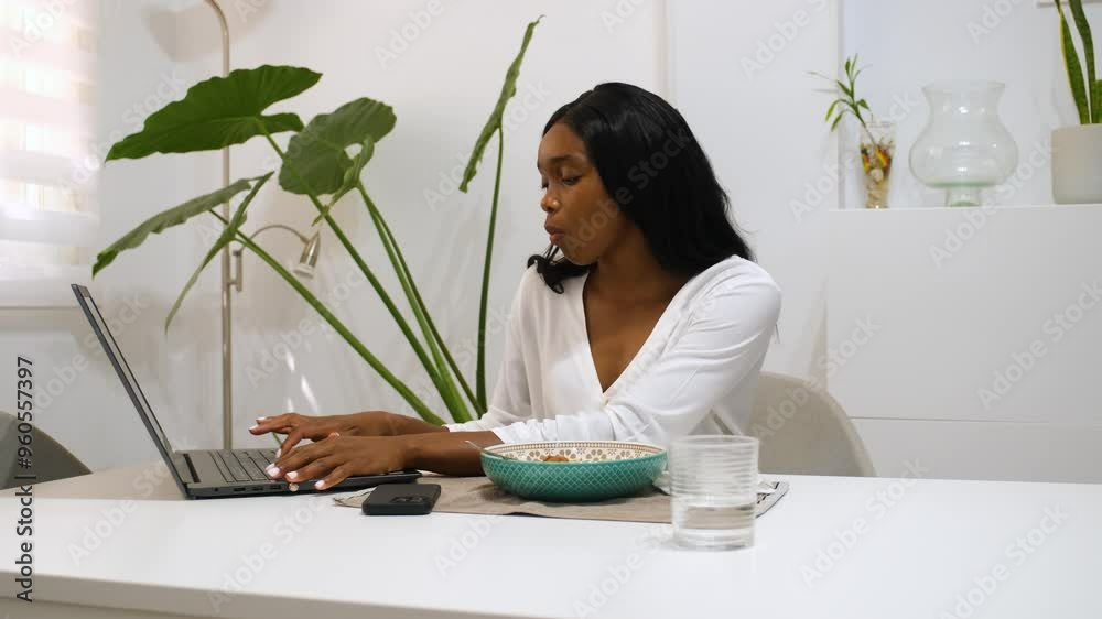 Businesswoman eats a healthy lunch of lentils while working on her laptop Businesswoman eats a healthy lunch of lentils while working on her laptop
