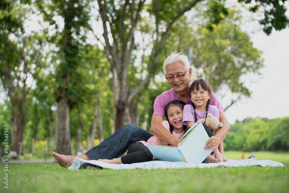 Happy Asian family children reading a book with her grandfather Happy Asian family children reading a book with her grandfather