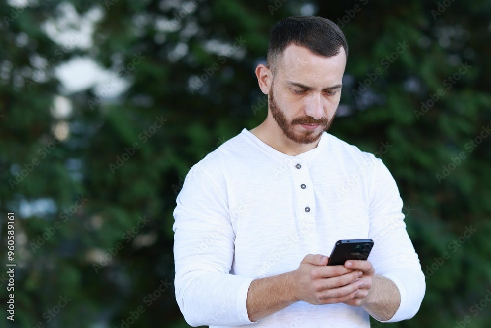 Handsome man using smartphone on blurred background. Space for text Handsome man using smartphone on blurred background. Space for text