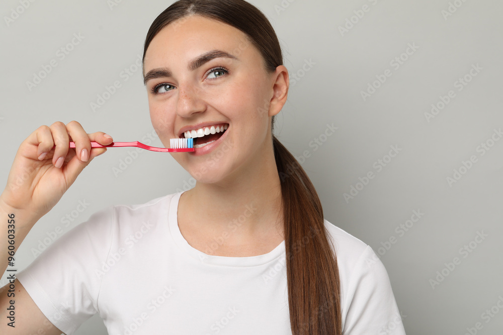 Beautiful woman brushing her teeth on gray background, space for text Beautiful woman brushing her teeth on gray background, space for text