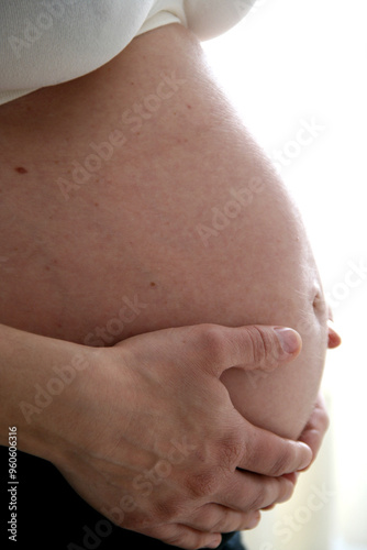 Pregnant woman. Woman with her bare belly and her hands hugging her baby. Concept of birth, pregnancy, fertility.