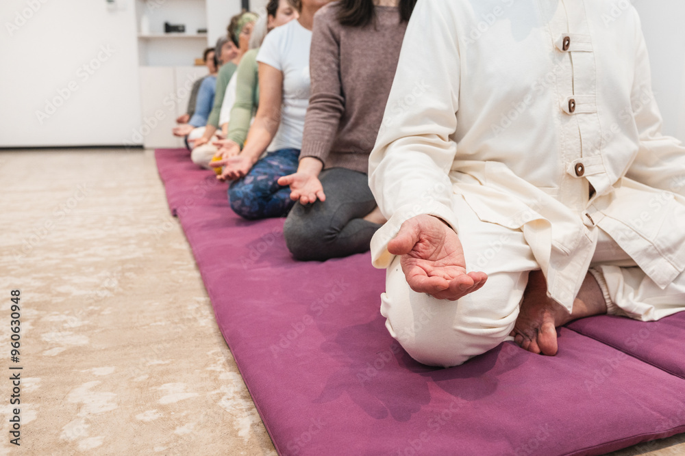 Fototapeta premium Yoga instructor and senior women practicing meditation in a row during a mindfulness session.