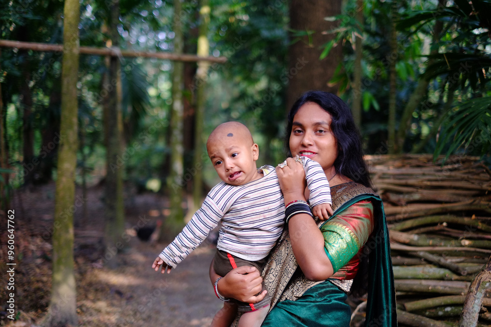 South asian young lady with a traditional costumes holding her baby boy in a garden South asian young lady with a traditional costumes holding her baby boy in a garden