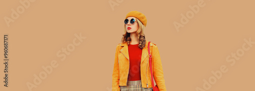 Autumn style, beautiful stylish young woman posing in orange hat, jacket on brown background