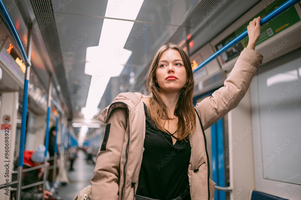 A young woman rides in a modern subway car. A beautiful girl in a jacket rides after work in the subway late A young woman rides in a modern subway car. A beautiful girl in a jacket rides after work in the subway late