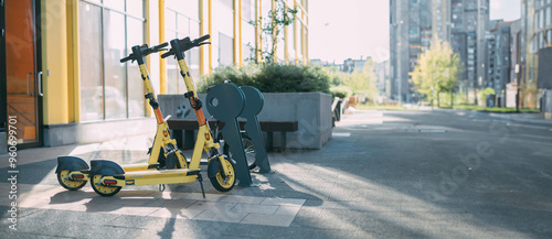 Electric scooter for rent on the street. Two bright scooters are parked on the sidewalk on a city street
