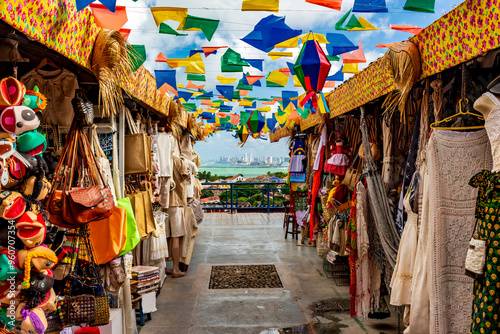 Fototapeta Naklejka Na Ścianę i Meble -  Brazilian street with shops for tourists in Olinda with a view of the city of Recife in the background