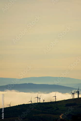 silhouette of a mountain range with wind turbine generators at sunset