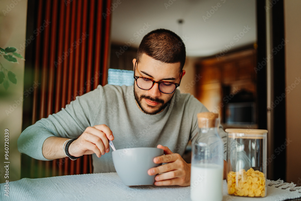 Young caucasian man eating corn flakes for breakfast at home Young caucasian man eating corn flakes for breakfast at home