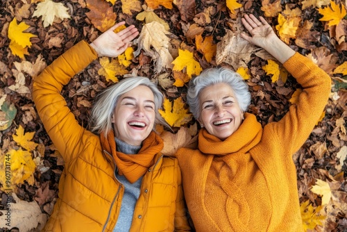 An autumnal scene of a grandmother and granddaughter lying on foliage