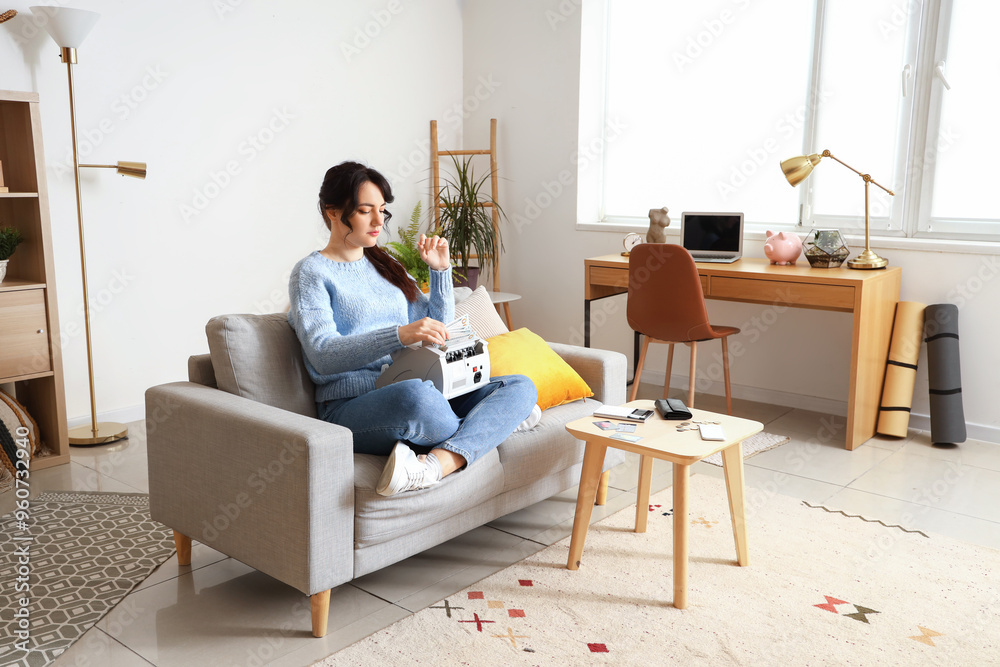 Young woman with cash counting machine at home