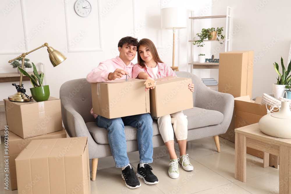 Young couple with keys and moving boxes in their new flat Young couple with keys and moving boxes in their new flat