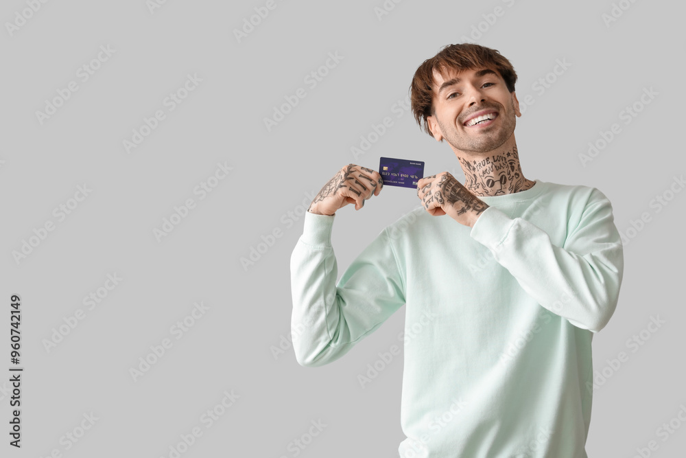 Tattooed young man with credit card on light background Tattooed young man with credit card on light background