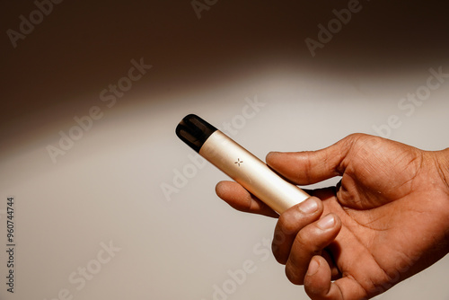 hand holding an e-cigarette on a black background with empty photocopy space.