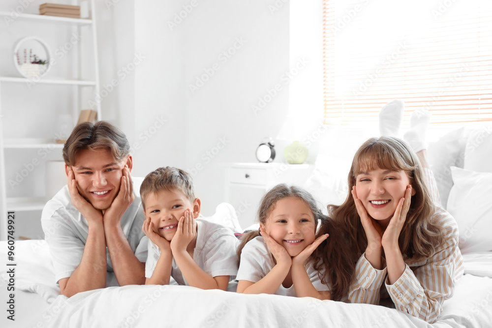 Happy parents with their little children lying in bedroom Happy parents with their little children lying in bedroom