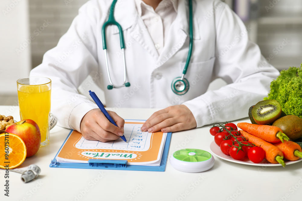 Young female nutritionist with healthy food and glass of juice writing diet plan in office, closeup Young female nutritionist with healthy food and glass of juice writing diet plan in office, closeup