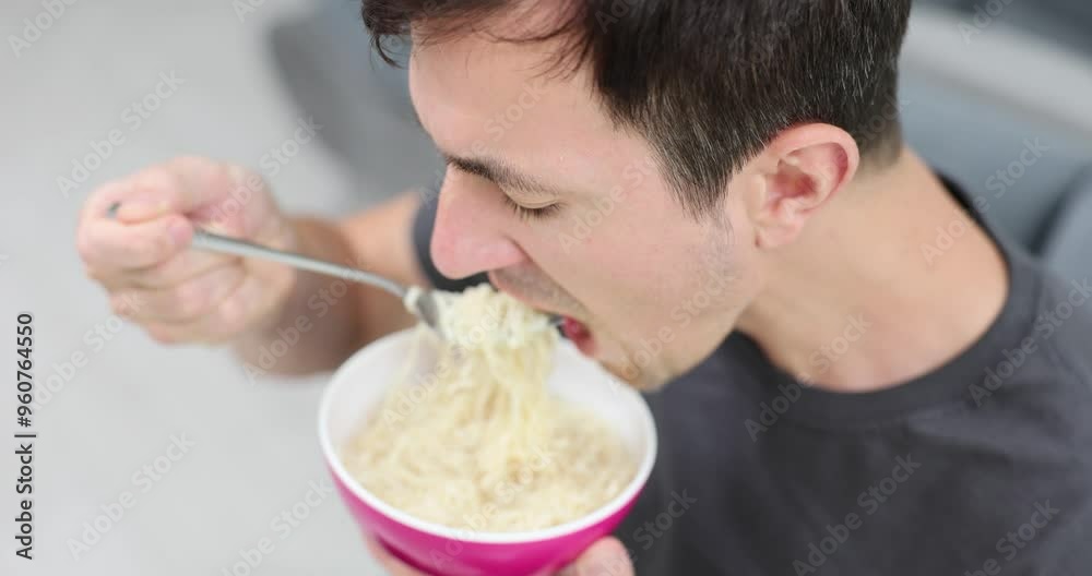 Male worker holds bowl eating instant noodles during lunch break in company office. Hungry man enjoys spicy taste of quick meal slow motion Male worker holds bowl eating instant noodles during lunch break in company office. Hungry man enjoys spicy taste of quick meal slow motion