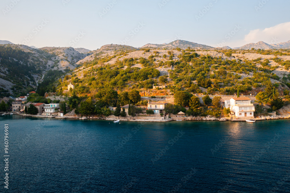 Arial view of a picturesque coastline with mountains and serene waters on a sunny day. Arial view of a picturesque coastline with mountains and serene waters on a sunny day.