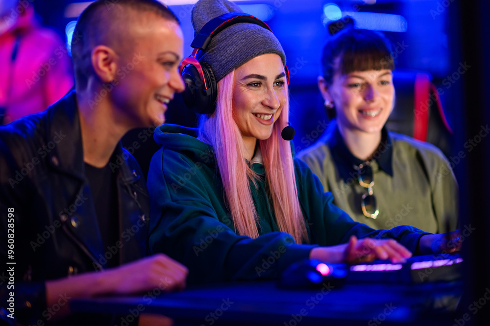 Gamer girl sitting in cybercafe with her friends and playing mmo rpg. Gamer girl sitting in cybercafe with her friends and playing mmo rpg.