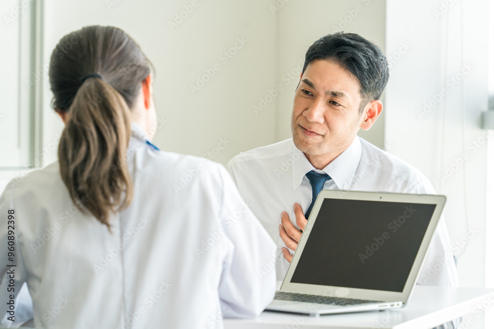 胸の痛みを医師に訴える中年男性（心臓病・不整脈・息切れ・動悸）
