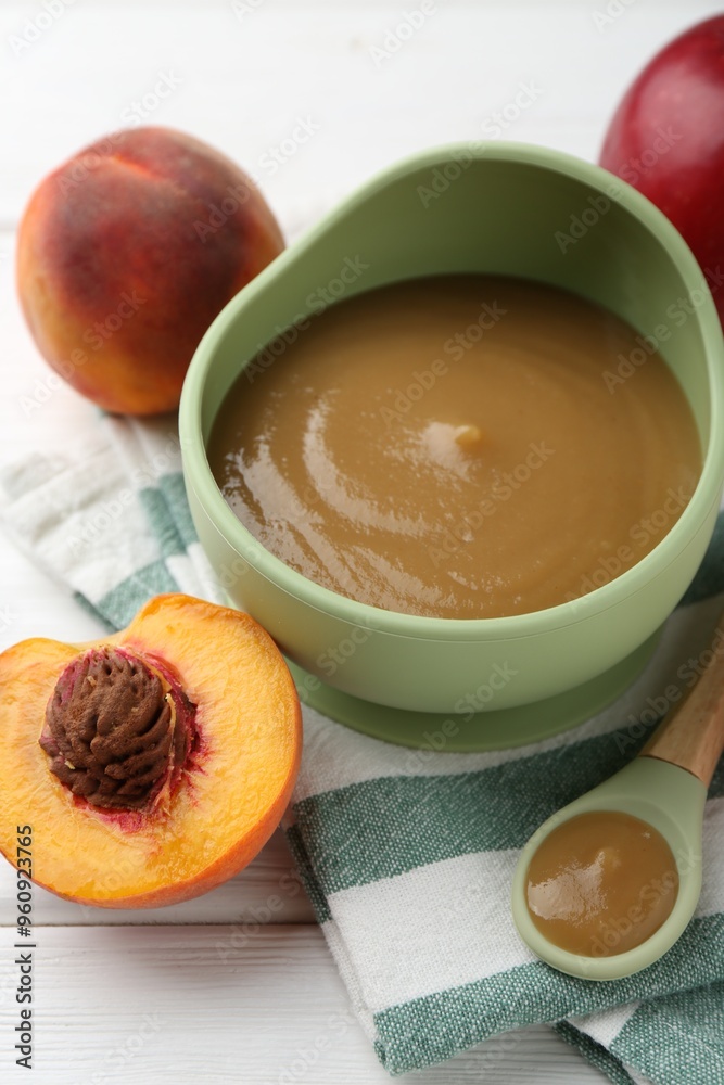 Delicious baby food in bowl and ingredients on white wooden table, closeup Delicious baby food in bowl and ingredients on white wooden table, closeup