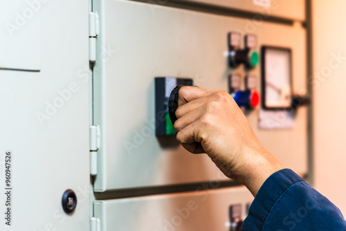 Fotografie A ship engineer's hand reaches toward a control panel, ready to activate a device