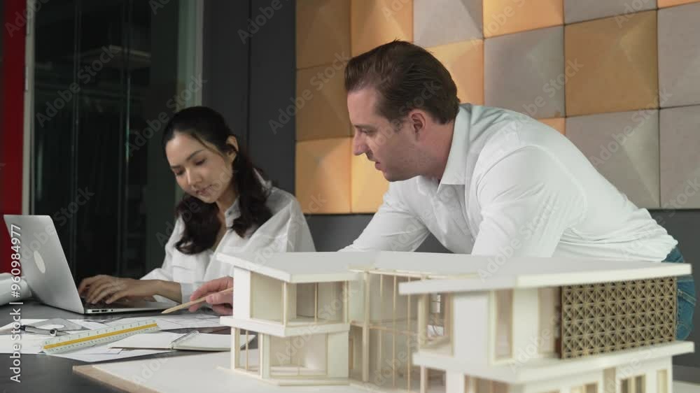 Skilled architect engineer working together to drawing house plan. Architect team discuss about house construction with architectural model, blueprint and laptop placed on office table. Manipulator. Skilled architect engineer working together to drawing house plan. Architect team discuss about house construction with architectural model, blueprint and laptop placed on office table. Manipulator.
