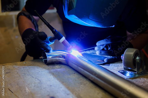 A man is welding a pipe with a blue flame