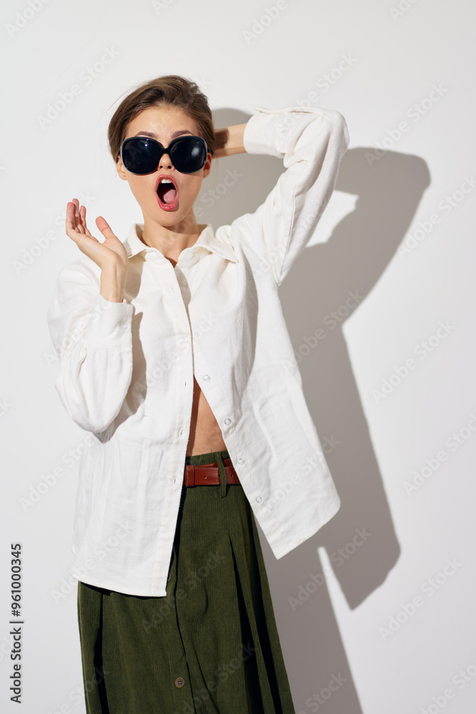 Fashion model in oversized sunglasses and a casual outfit expressing surprise against a white background, highlighting contemporary style and playful attitude in photography Fashion model in oversized sunglasses and a casual outfit expressing surprise against a white background, highlighting contemporary style and playful attitude in photography