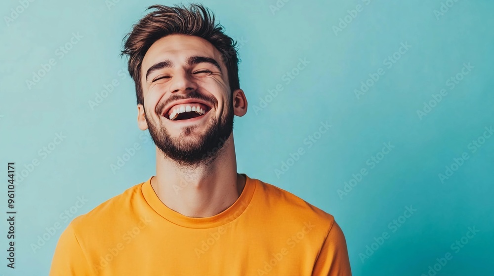 Portrait of a happy handsome man in a orange shirt, laughing against a blue background with copy space Portrait of a happy handsome man in a orange shirt, laughing against a blue background with copy space